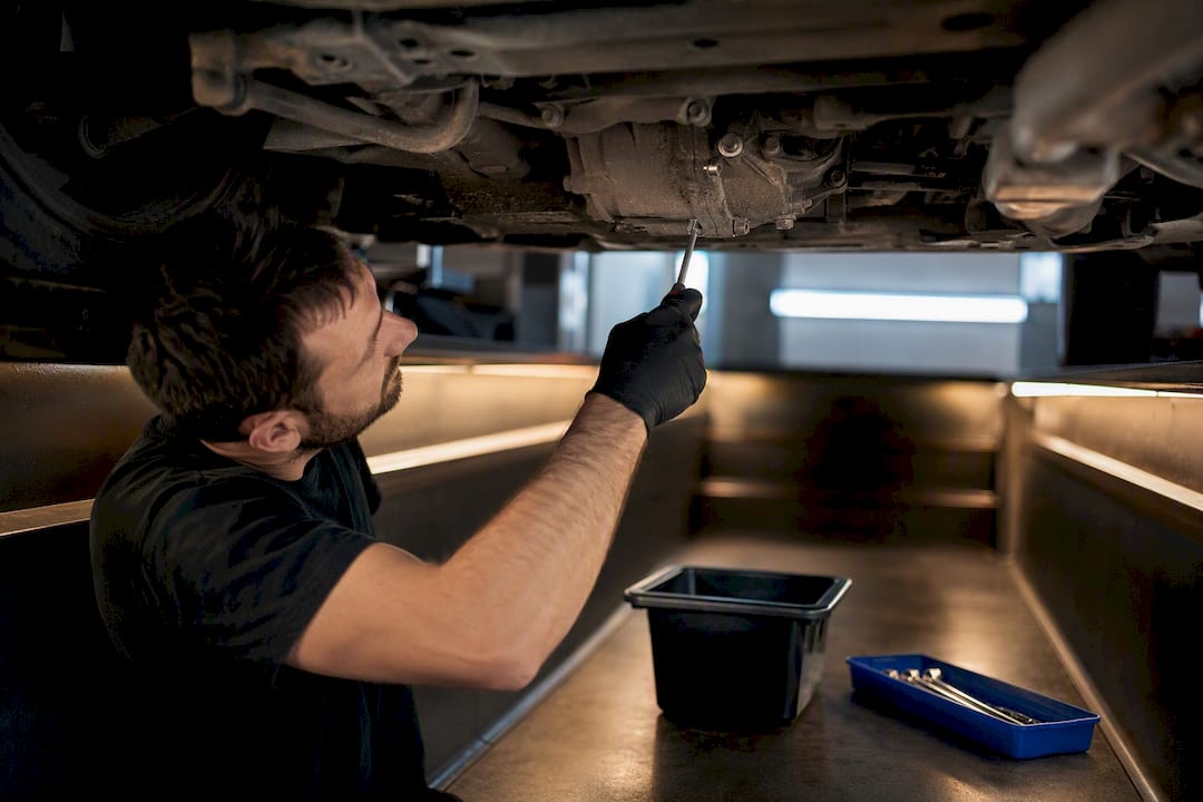 Technician servicing anonymous AWD coupling underside